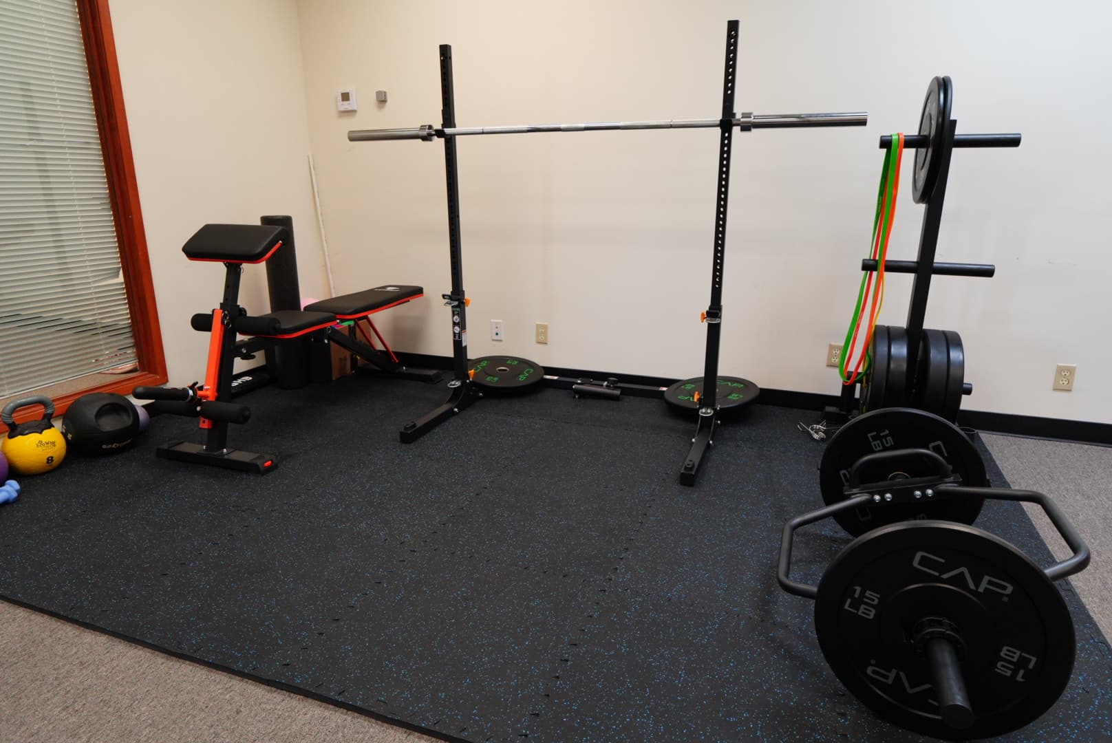 Exercise space with a squat rack, bench, weights, and kettlebells